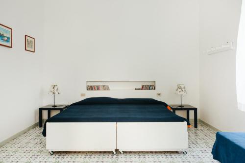 um quarto branco com uma cama grande e um cobertor azul em Casa Carlotta em Stromboli