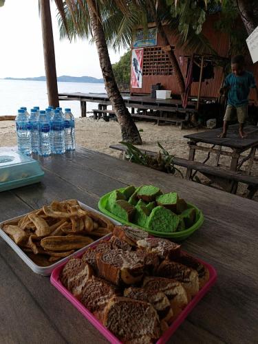 a table with a tray of bread and chips and water bottles at Gloria Dive Homestay in Keruo