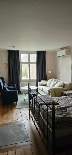 a bedroom with a bed and a living room with a couch at STF Glasbruket Hostel & Apartments in Borensberg
