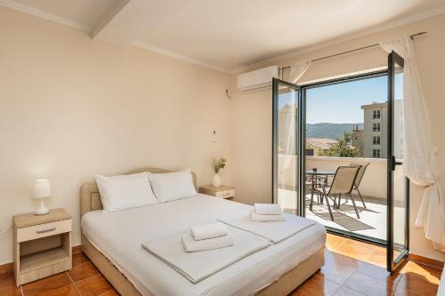 a white bedroom with a bed and a balcony at Apartmani Jakšić in Meljine