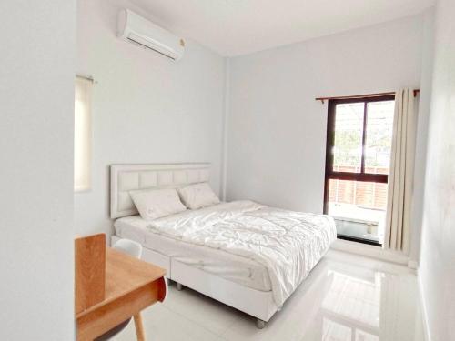 a white bedroom with a bed and a window at ลิบเบล โฮมสเตย์ in Ban Nong Sa