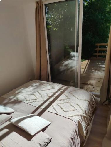 a bed in a room with a sliding glass door at Le nid douillet in Aydat