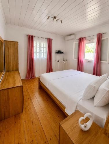 a bedroom with a large white bed and red curtains at Stone & Sea Retreat in Órmos Marathokámpou