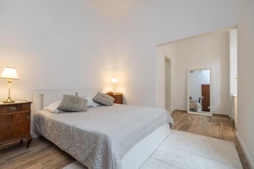 a white bedroom with a bed and a mirror at Apartment and Rooms Stay in Dubrovnik