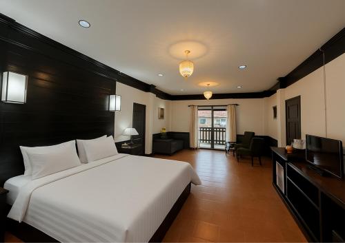a bedroom with a large bed and a living room at Silamanee Resort & Spa Hotel in Mae Sai