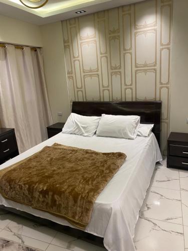 a bedroom with a large bed with a brown blanket on it at اهرمات بورتو السخنه in Madinaty