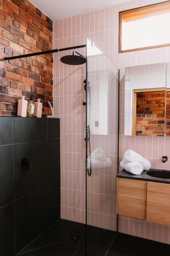 a glass shower in a bathroom with pink tiles at Charm on Forster in Invermay
