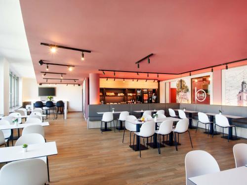 a restaurant with white tables and white chairs at B&B HOTEL Rüsselsheim in Rüsselsheim