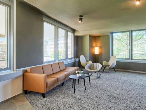 a waiting room with a couch and chairs and windows at B&B HOTEL Rüsselsheim in Rüsselsheim