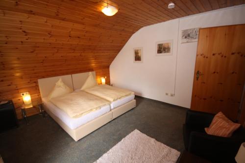 ein Schlafzimmer mit einem weißen Bett in einer Holzdecke in der Unterkunft Gasthof Küssaburg in Küssaberg