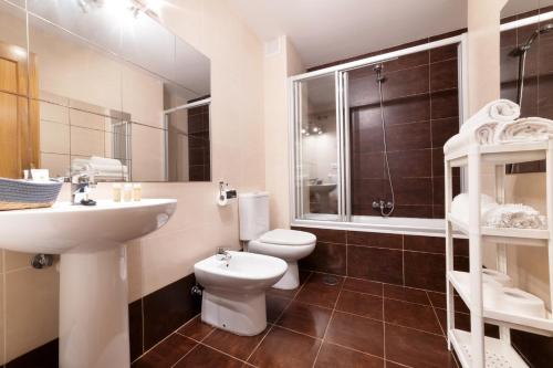 a bathroom with a white toilet and a sink at Apartamentos El Escudo Centro in Ribadesella