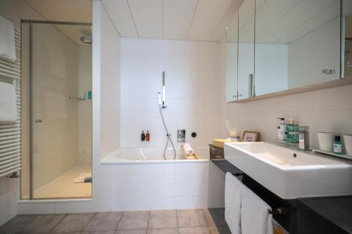 a bathroom with a tub and a sink and a shower at Swiss Luxury Apartments Geneva - Serviced Apartments in Geneva