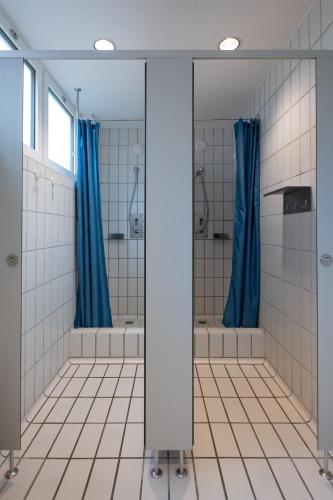 a bathroom with blue shower curtains and tile floors at Zug Youth Hostel in Zug