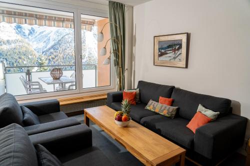 a living room with a couch and a table and a window at Edelweiss in Arosa