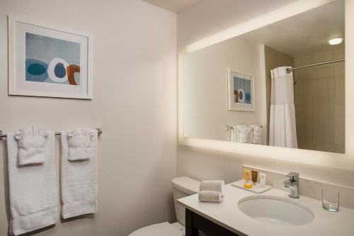 a bathroom with a sink and a toilet and a mirror at Corporate Inn Sunnyvale - All-Suite Hotel in Sunnyvale