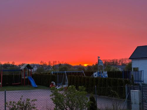 a sunset over a playground with a red sky at Sosnowe Domki in Sarbinowo