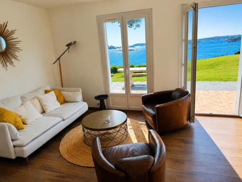 a living room with a white couch and chairs at La Bretonne vue mer in Lanmodez