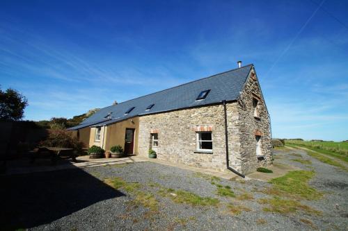 a stone house with solar panels on the roof at Y Felin - The Mill in St. Davids