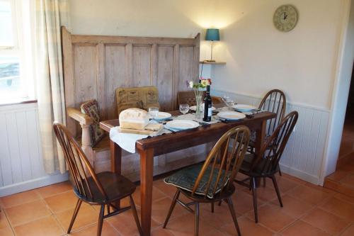 a dining room table with chairs and a clock on the wall at Y Felin - The Mill in St. Davids