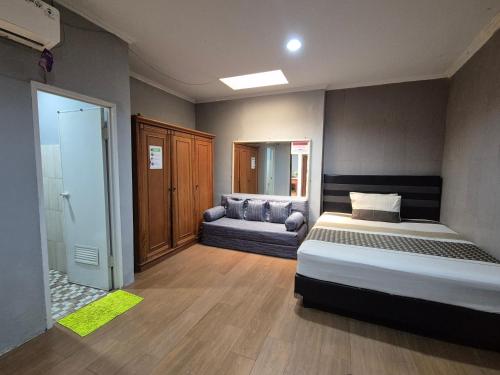a bedroom with a bed and a couch in it at Maninjau House in Jakarta