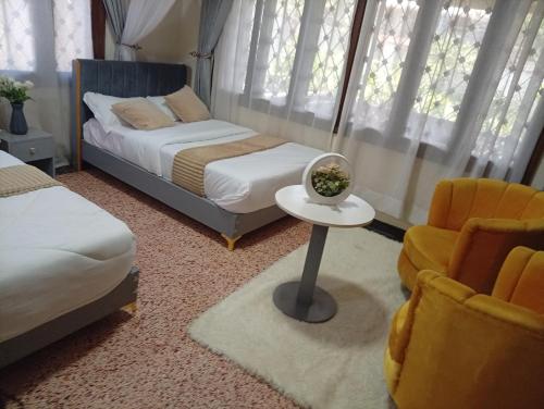 a bedroom with two beds and a table and a chair at Spring homes2 in Jinja
