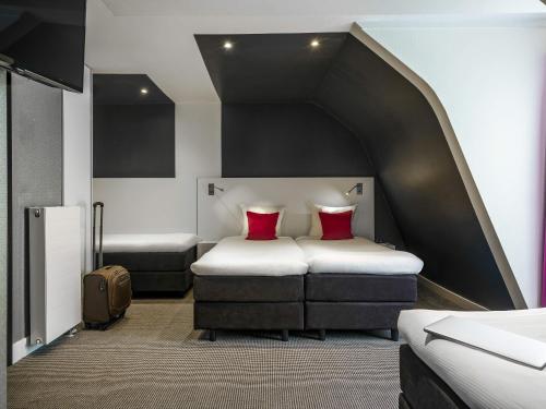 a room with two beds with red pillows at ibis Styles Amsterdam Amstel in Amsterdam