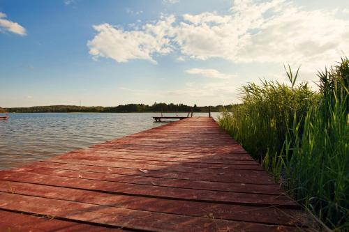 a wooden bridge over a body of water at Pajda Mazur - Ośrodek wypoczynkowy in Stare Jabłonki