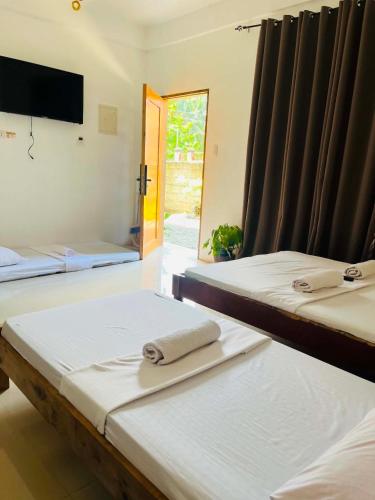 two beds in a room with a tv on the wall at Sapayag Backpacker's Inn in Dipolog
