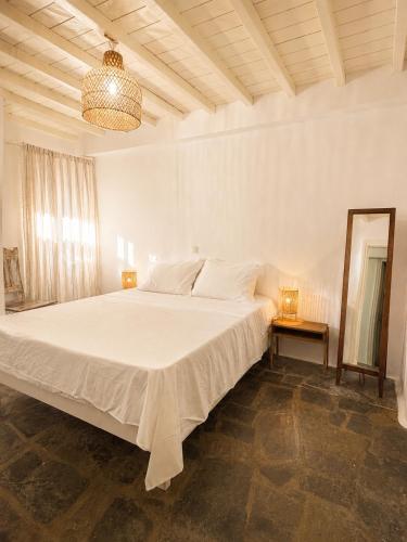 a large white bed in a white bedroom with a mirror at Cozy Summer House in Mikonos