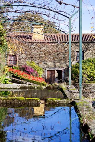 a stone building with a pond in front of it at Quinta de Mourães - Casa do Xisto in Lever