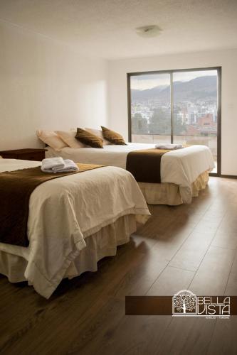 two beds in a room with a large window at Hotel Bellavista Quito in Quito