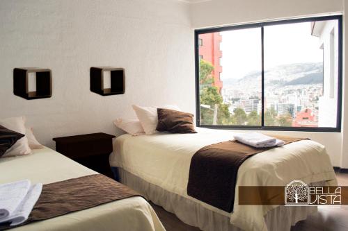 two beds in a room with a large window at Hotel Bellavista Quito in Quito