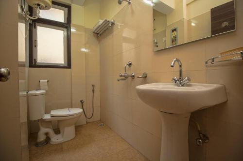 a bathroom with a sink and a toilet at Hotel O Kshounish Residency in Mālda