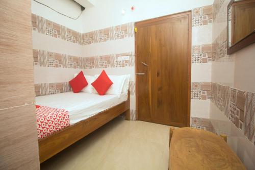 a small bedroom with a bed with red pillows at Hotel O Kshounish Residency in Mālda