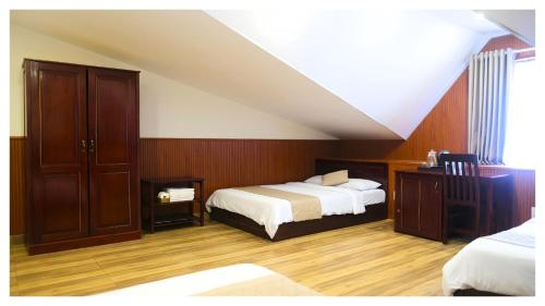 a bedroom with a bed and a dresser at Nam Xuan Premium Hotel in Da Lat