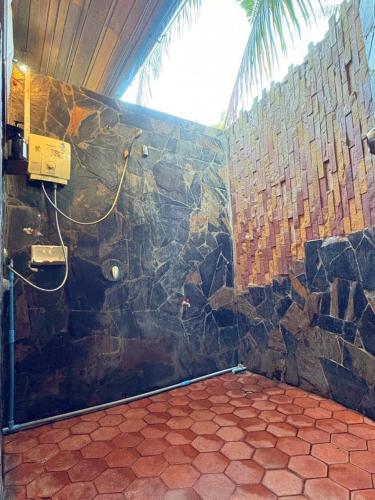 a bathroom with a shower with a stone wall at Koh Talu Island Resort in Bang Saphan Noi