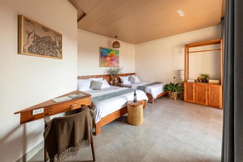 a bedroom with two beds and a desk and a mirror at Ban Mai Village in Phú Hiệp