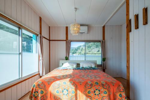 a bedroom with a bed in a room with a window at Sotoura Sunrise Cottage 30m from Beach in Shimoda