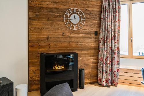 a fireplace in a living room with a wooden wall at Terra Alpina in Arosa