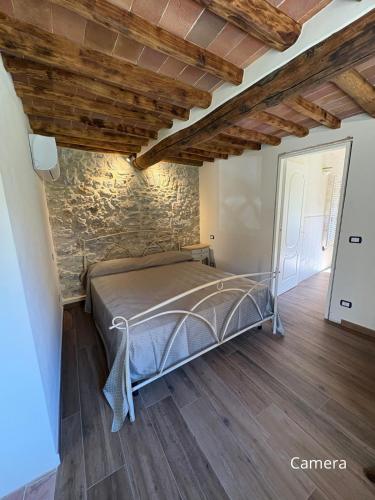 a bedroom with a bed in a room with a stone wall at Cà del Bosco Appartamento Castagno in Il Romito
