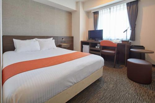 a hotel room with a bed and a desk with a computer at Rembrandt Hotel Tokyo-Machida in Machida