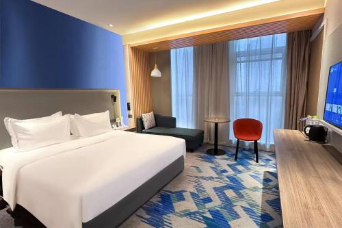 a hotel room with a large white bed and a red chair at Holiday Inn Express Linyi West by IHG in Linyi