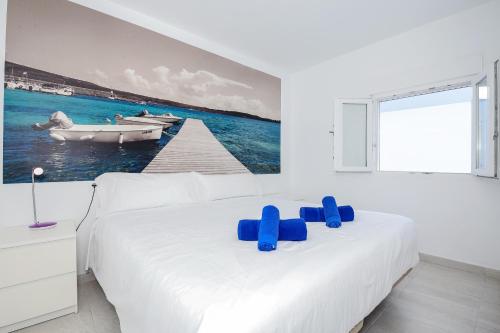 a white bedroom with a bed and a boat in the water at Villa Garasa in Cala Blanca