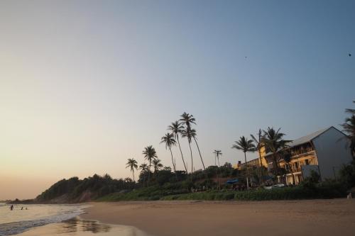 a beach with palm trees and a building on it at The Seascape in Matara