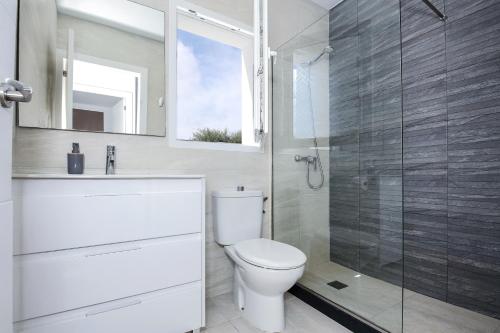 a bathroom with a toilet and a glass shower at Villa Garasa in Cala Blanca