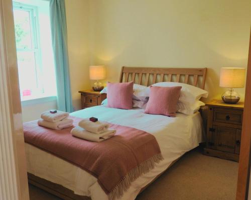 a bedroom with a bed with two towels on it at Foxglove Cottage in Killean