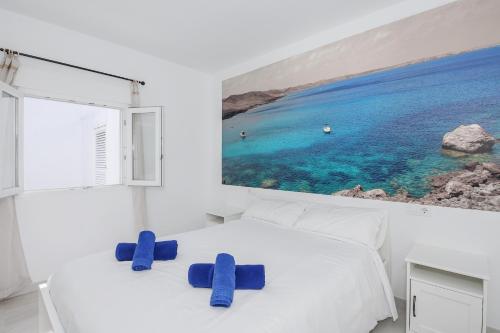 a white bedroom with blue chairs on a bed at Villa Izarenar in Cala Blanca