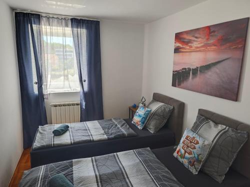 a bedroom with two beds and a window with a painting at Apartmani Kaja, Vantačići, Otok Krk, A1 in Vantačići