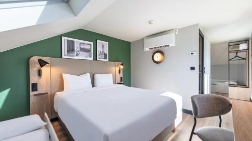 a bedroom with a white bed and a green wall at Campanile NATURE - Lille Wasquehal in Wasquehal