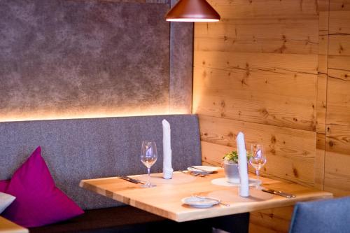 a wooden table with two wine glasses on it at SPA & Naturhotel Outside in Matrei in Osttirol
